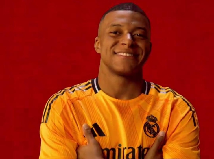 Mbappè con indosso la nuova maglia arancione del Real Madrid 